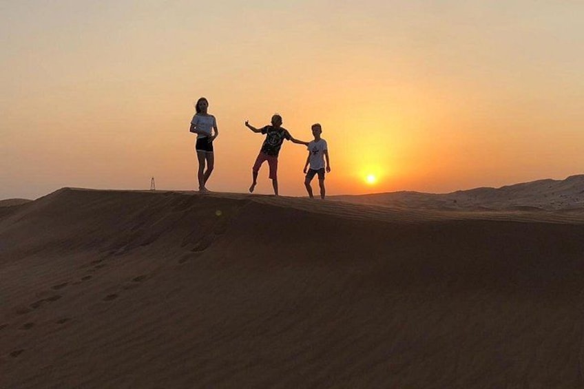 Three people playing on sand dunes during sunset. 5