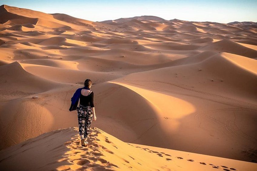 A person walking on a sand dune in a desert landscape. 4