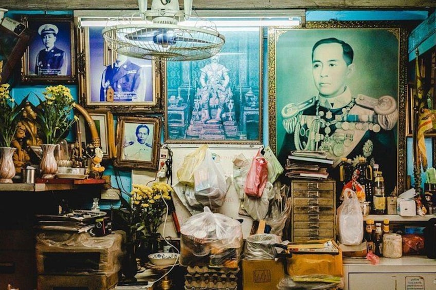 A cluttered room with various items, including framed pictures, a fan, and miscellaneous objects. 4