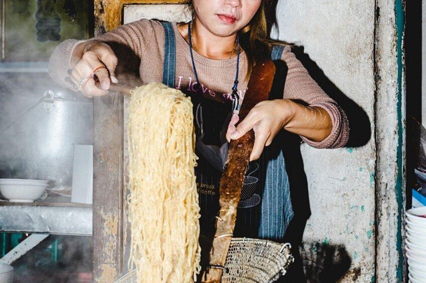 Una persona cucina noodles con una pentola grande e un cucchiaio di legno. 3