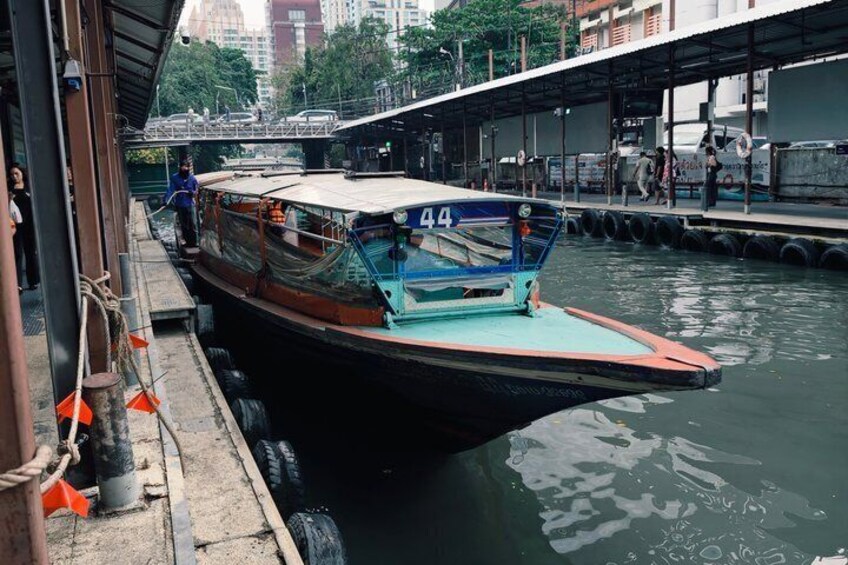 A boat docked at a pier with a number 44 sign, surrounded by water and urban buildings. 2