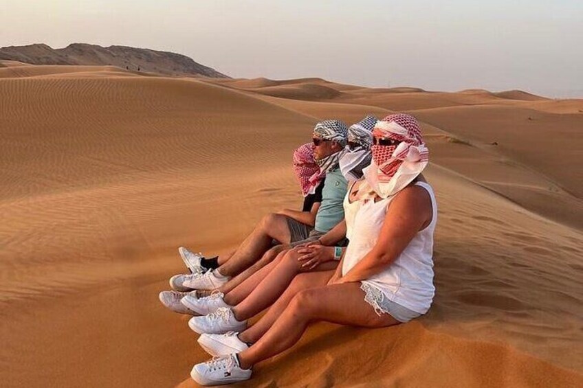 Personas sentadas sobre una duna de arena en un paisaje desértico. 3