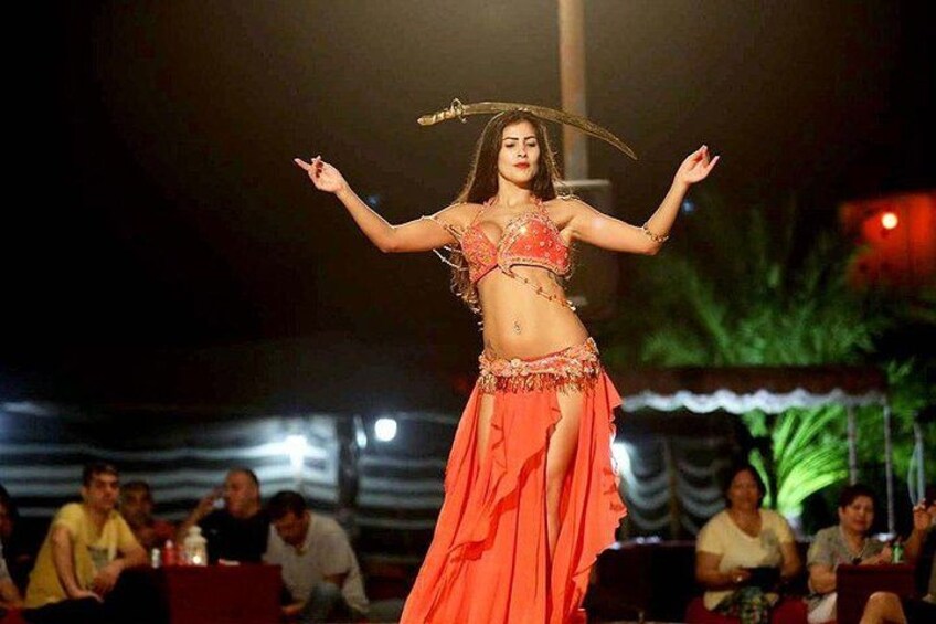 Una persona bailando en un escenario, con una audiencia sentada al fondo. 4