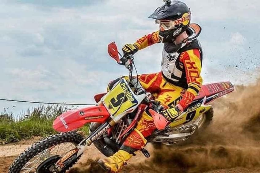 A motocross rider on a red dirt bike in mid-air, wearing a yellow and red suit. 1