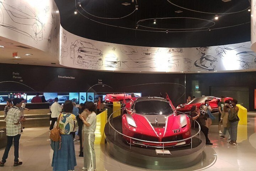 Un auto deportivo rojo en exhibición, con gente alrededor. 5