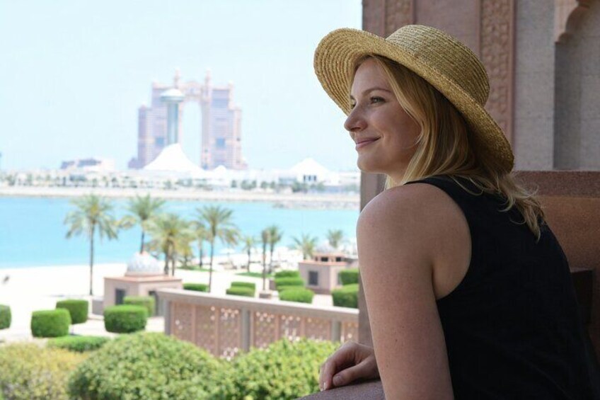 A person wearing a straw hat overlooking a coastal area with palm trees and a large building in the background. 4