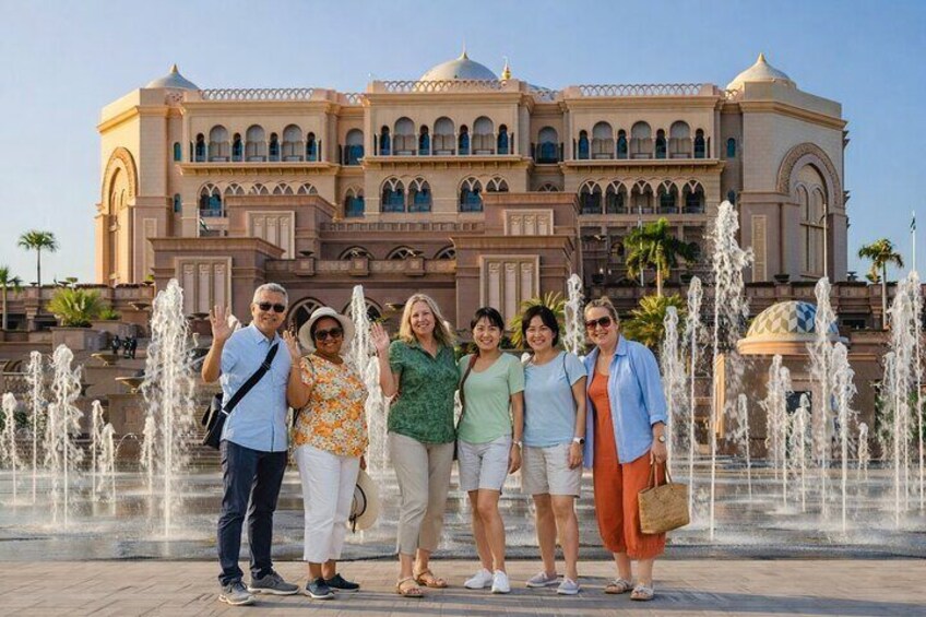 A group of people standing in front of a large building with a fountain in the background. 5