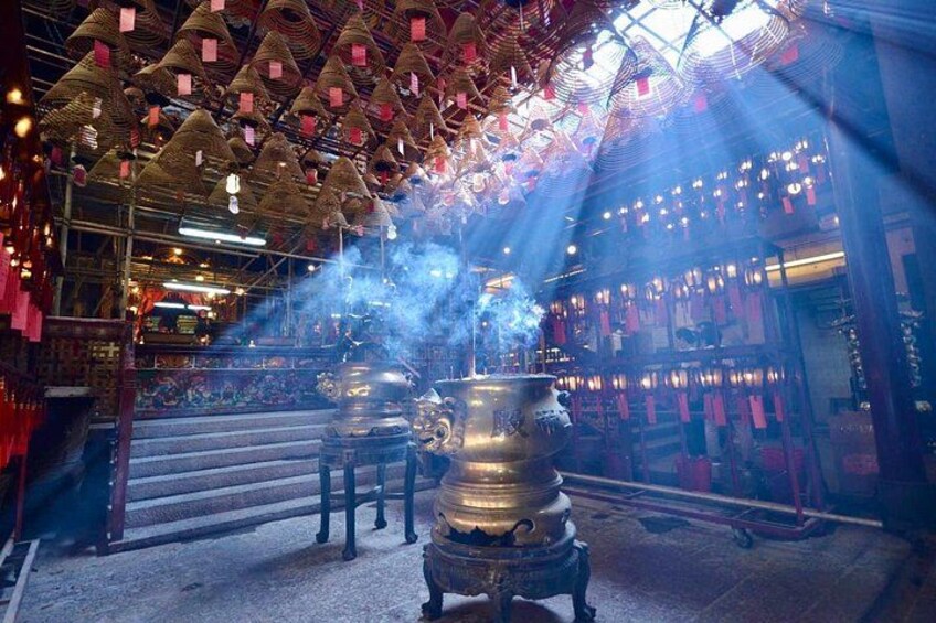A temple interior with incense burners, a staircase, and hanging decorations. 2