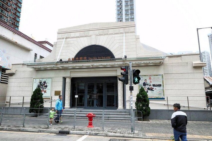 A theater building with a large arched entrance, a traffic light, and a red fire hydrant. 2