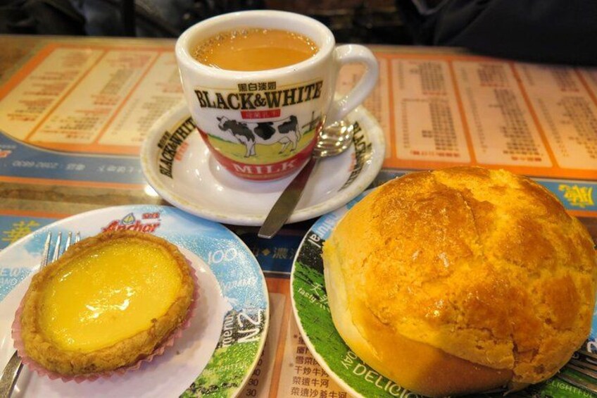 Una mesa con una taza de café Black & White, un muffin y un pastel. 1