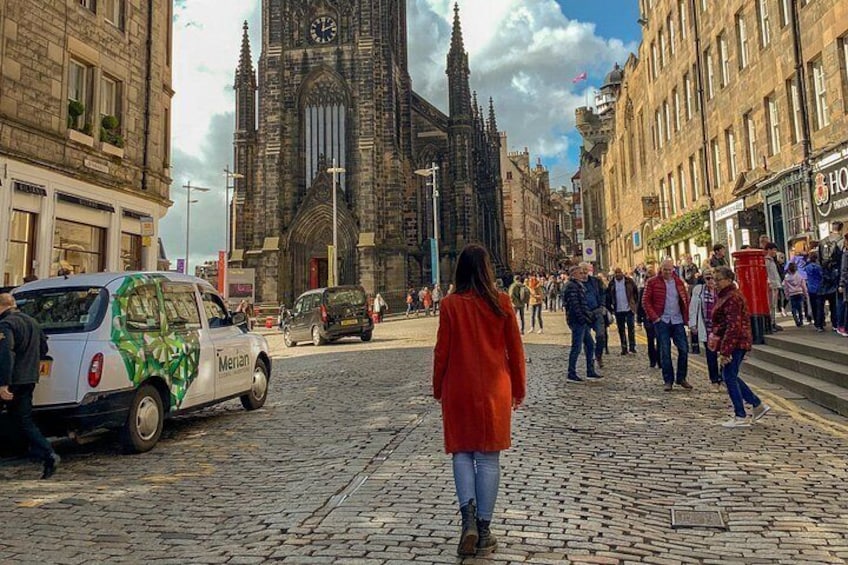 Una calle empedrada con una iglesia histórica, una camioneta blanca y gente caminando. 5