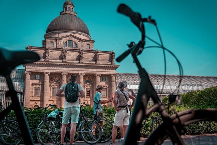 A large building with a dome, people standing in front of it, and bicycles. 4