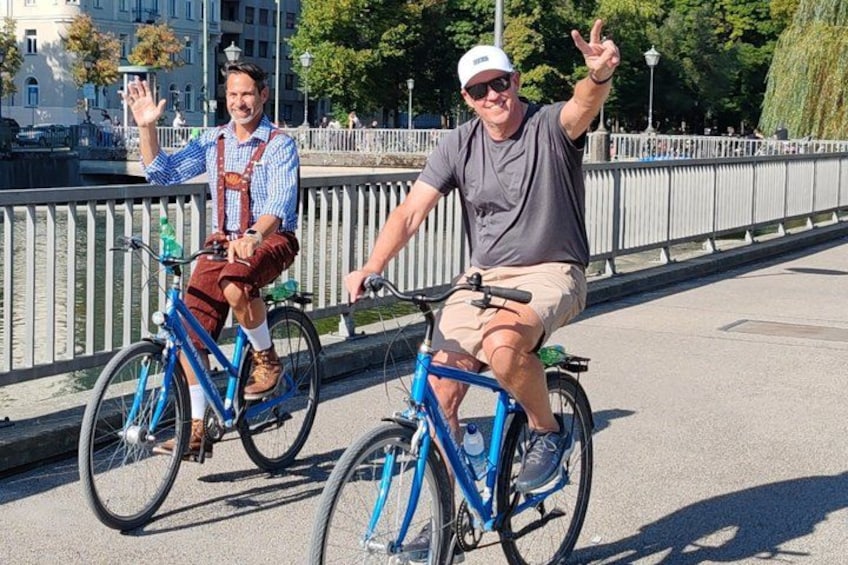 Due persone che vanno in bicicletta su un ponte con una ringhiera e un corso d'acqua sullo sfondo. 3