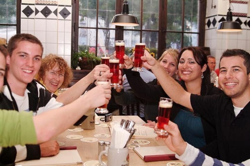 A group of people toasting with beer glasses at a table in a restaurant. 5