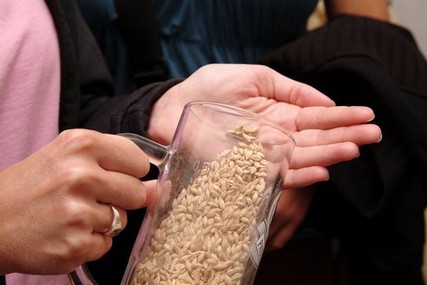 A person pouring grains from a glass container into their hand. 1