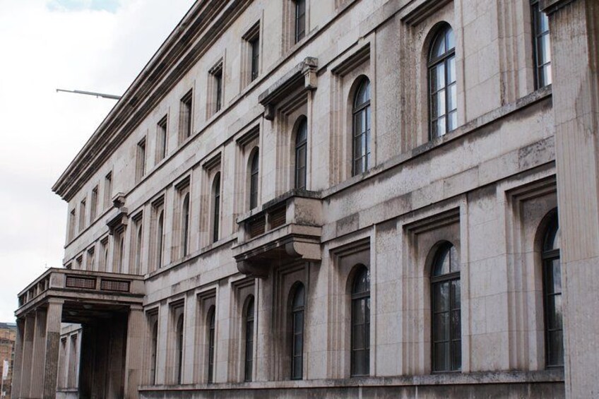 Un edificio grande e histórico con arquitectura clásica, que presenta múltiples ventanales en arco y una entrada destacada. 1