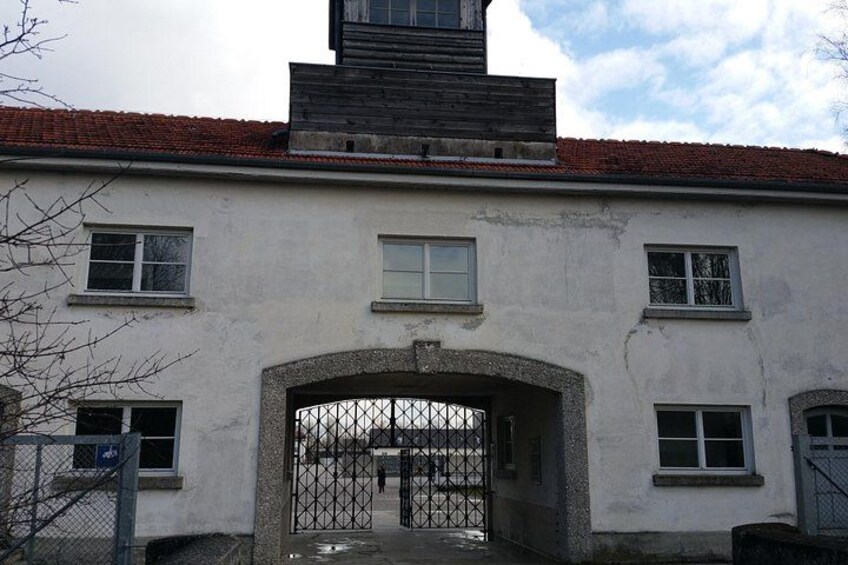 Un edificio blanco con techo de tejas rojas, una reja de metal y varias ventanas. 5