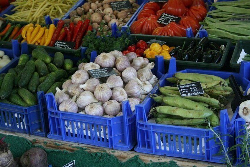 Un mercado con diversos vegetales como pepinos, ajo y pimientos en cajas azules. 2