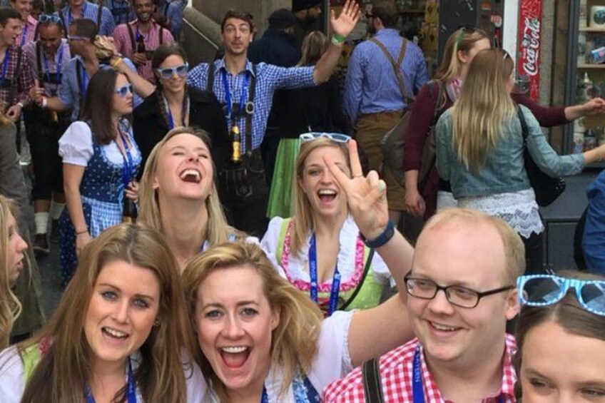 Un groupe de personnes, vêtues de costumes traditionnels bavarois, notamment des dirndls et des lederhosen, s’est rassemblé à l’extérieur. 3