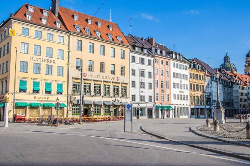 A street with historic buildings, a Rolex store, and a statue. 5
