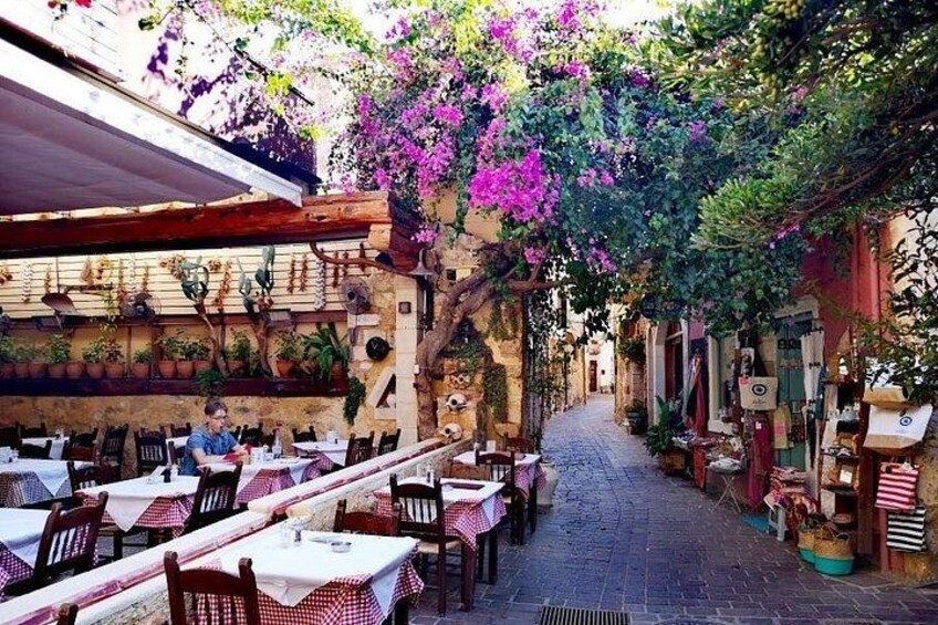 An outdoor café with tables and chairs, surrounded by potted plants and flowering vines. 1