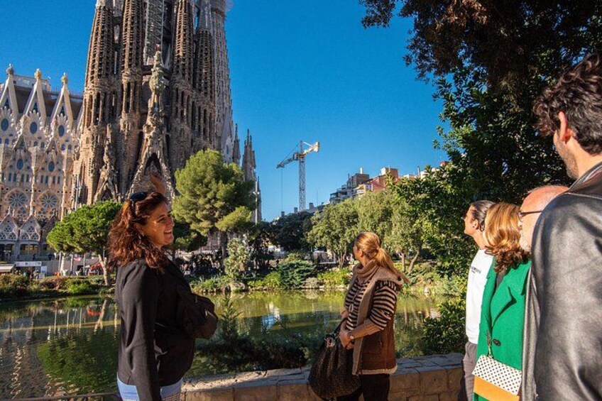A group of people standing by a water body with a large cathedral in the background. 2