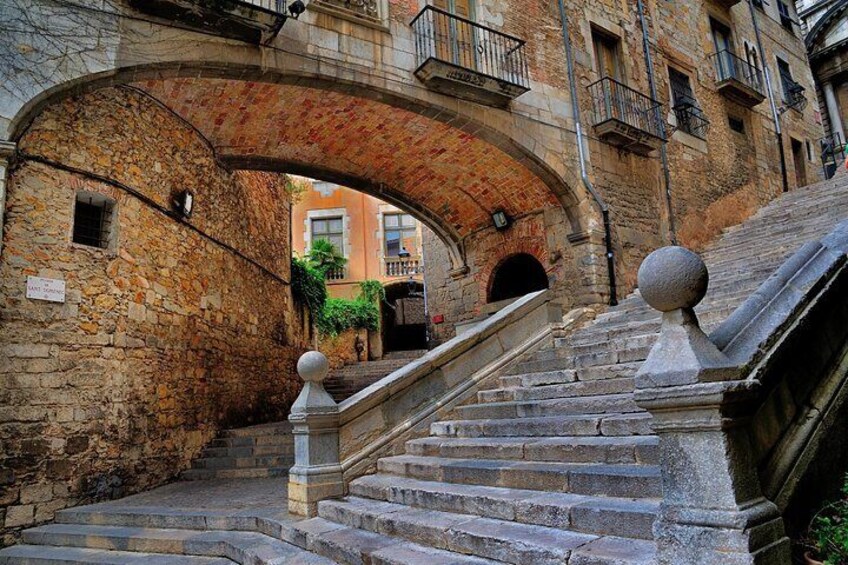 A stone staircase under a brick archway with a balustrade. 1