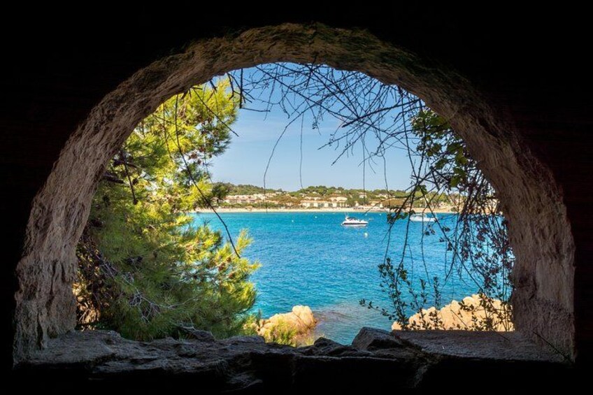 Vista costera a través de un arco de piedra, con un barco en el agua y una costa distante. 4