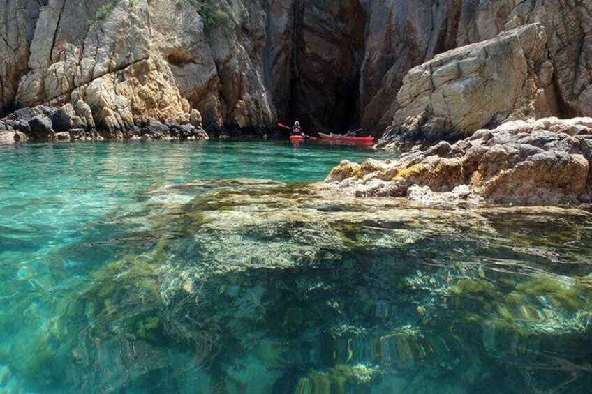 Agua turquesa cristalina, formaciones rocosas y un kayak rojo. 5
