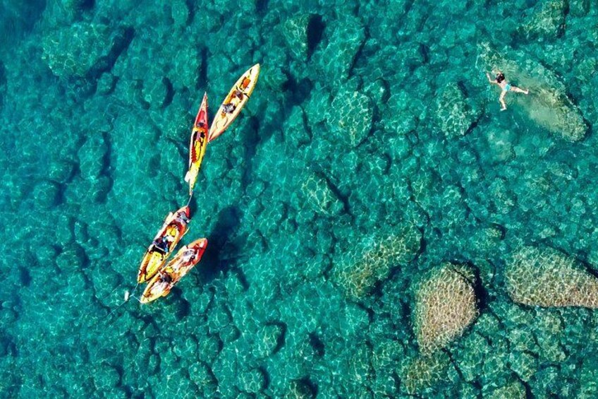 Kayaks en un mar turquesa transparente con terreno rocoso sumergido. 1