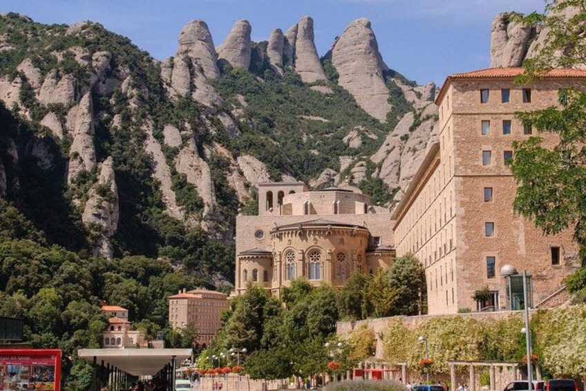 A historic building with a dome, surrounded by rocky mountains and lush greenery. 1