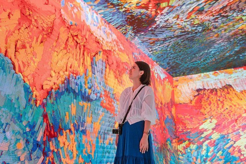 A person standing in front of a colorful, textured wall. 3