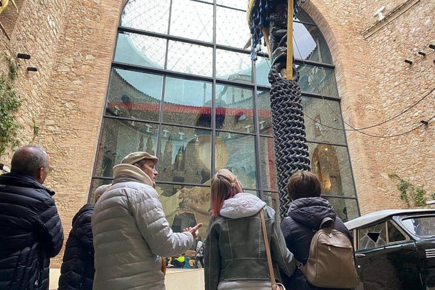 People looking through a large window at a building with a chain decoration. 4
