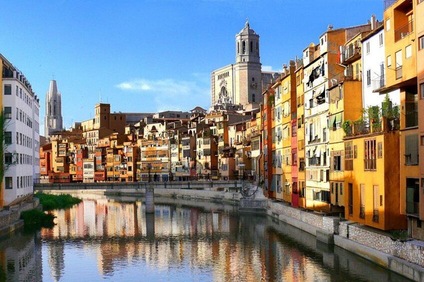 A canal with buildings reflecting on the water, a tower, and a church in the background. 2