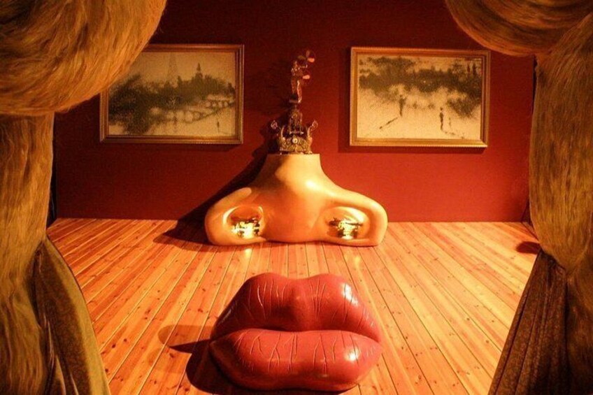 A room with wooden flooring, a red chair, and two framed paintings on the wall. 4