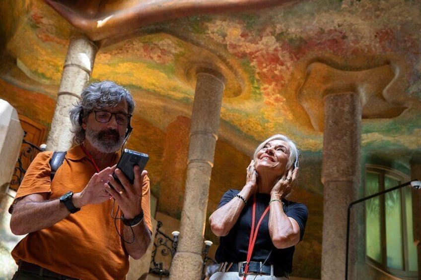 Two people inside a building with a colorful ceiling and columns. 3