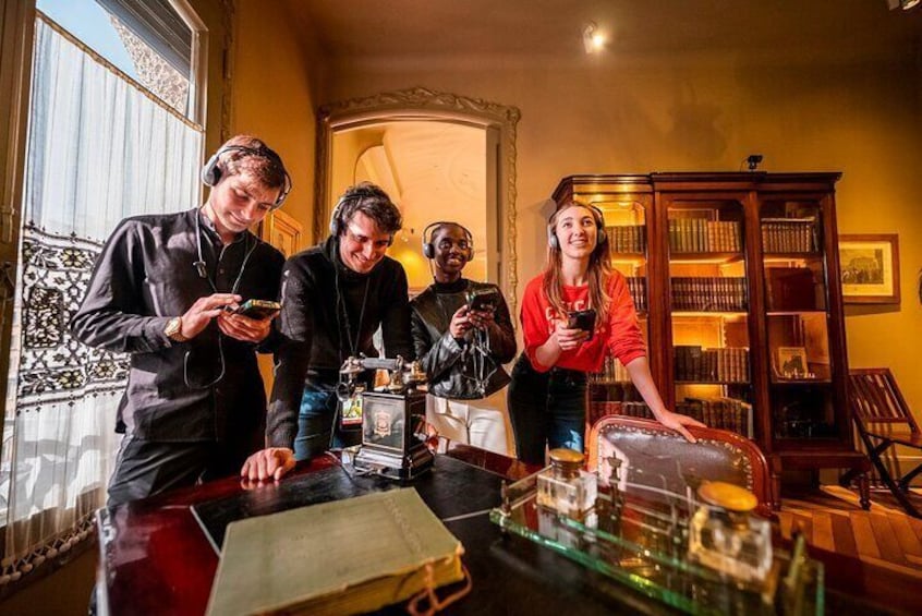 A group of people in a room with a table, bookshelves, and a piano. 4