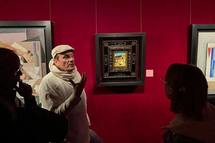 An art gallery with framed paintings on red walls. 2