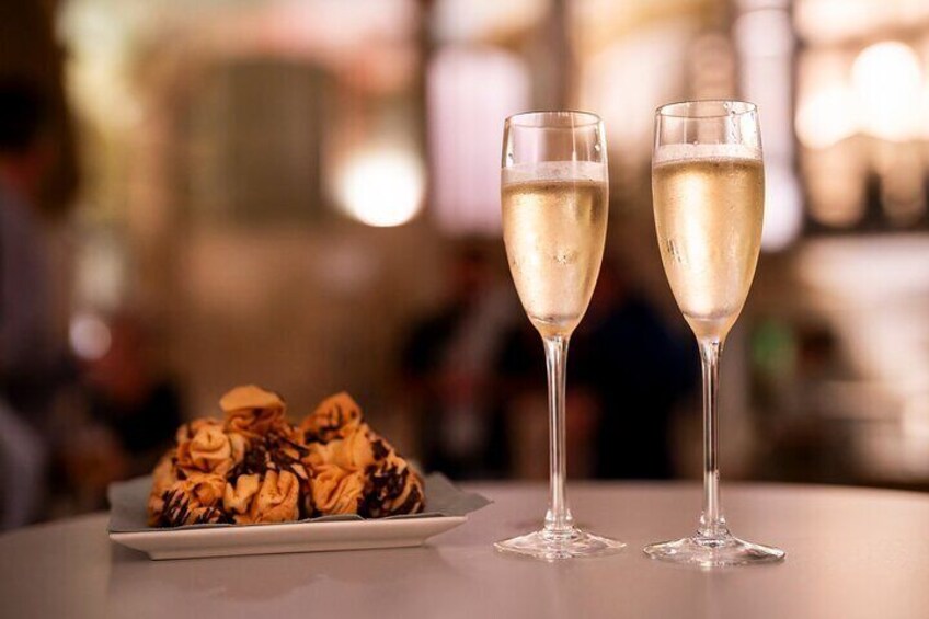 Two champagne flutes on a table with a plate of pastries. 2