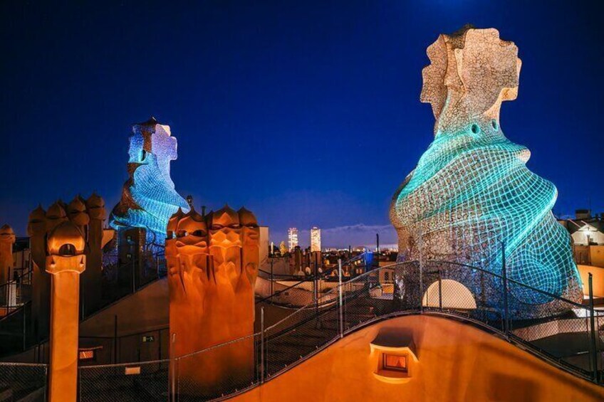 A nighttime view of a cityscape with illuminated sculptures and a bridge. 1