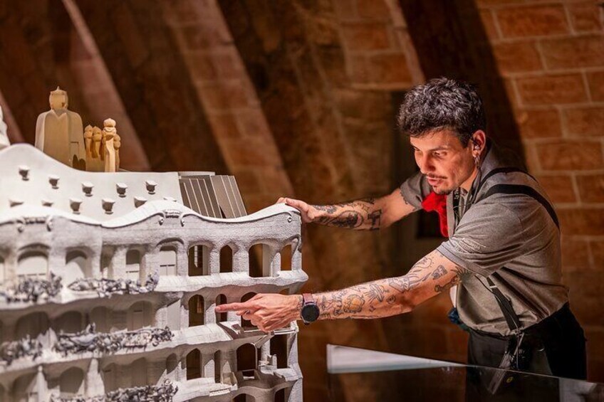 A person working on a detailed model of a historical building with arches and figures. 3