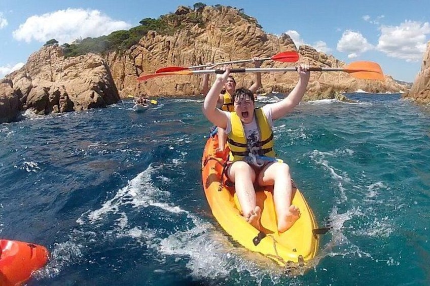 A person kayaking on a yellow raft in a body of water with rocky cliffs in the background. 3