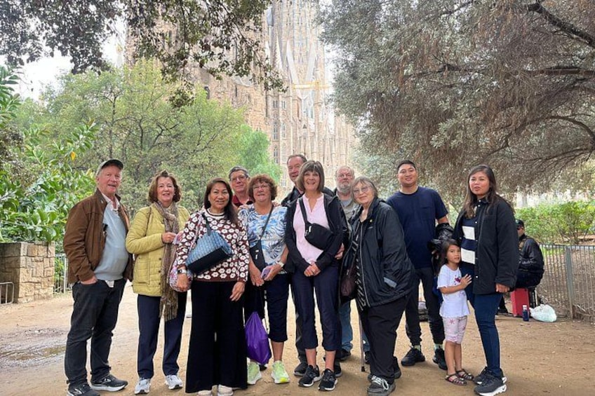 A group of people standing outdoors with trees and a building in the background. 2