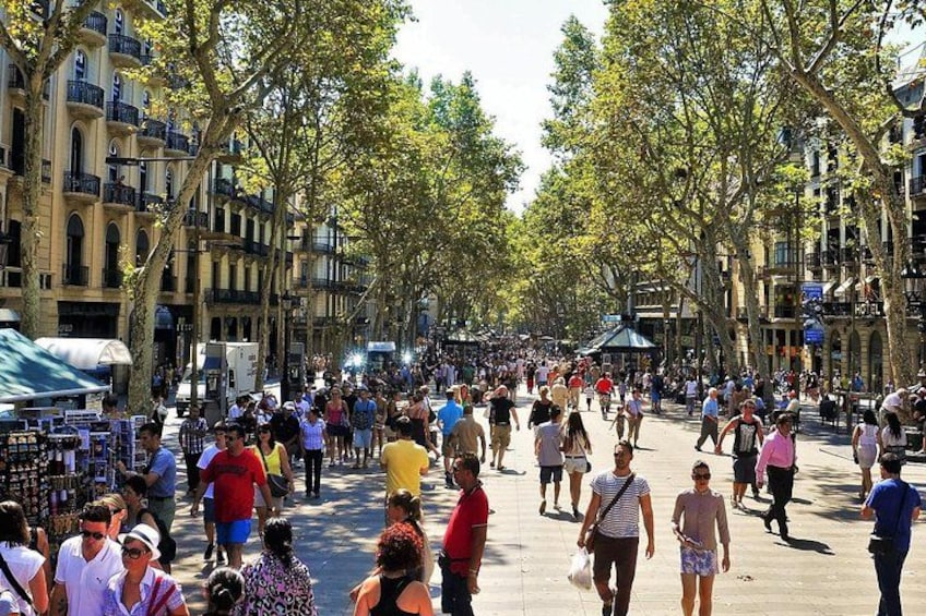A crowded pedestrian street lined with trees and buildings. 2