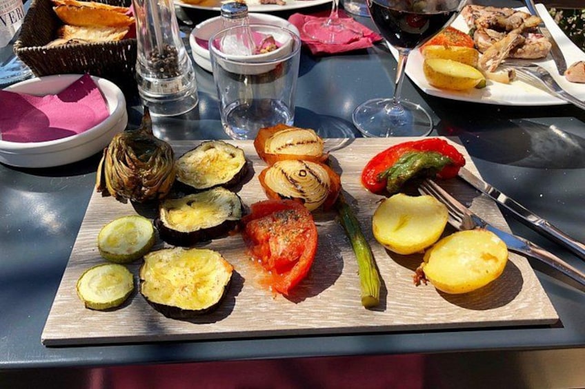 A wooden board with sliced vegetables and a glass of red wine on a table. 3