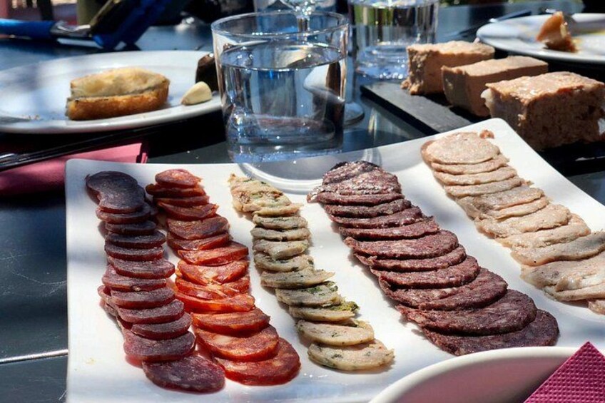 A variety of sliced meats on a white plate. 5