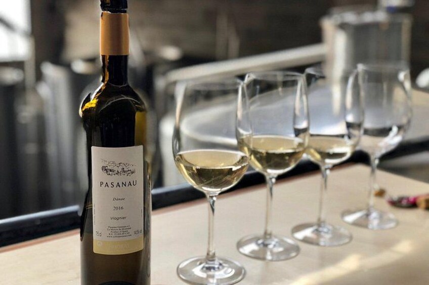 A bottle of Pasanaú wine and four wine glasses on a table. 4