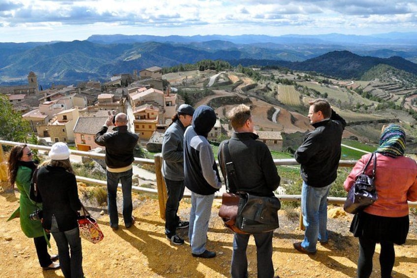 A group of people standing on a hill overlooking a village with terraced fields and a church. 2