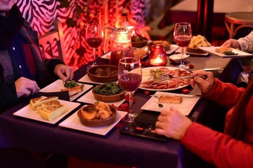 Una mesa de comedor con comida, copas de vino y una vela. 1