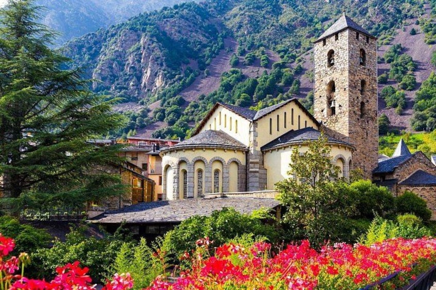 A church with a bell tower, surrounded by lush greenery and flowers. 1